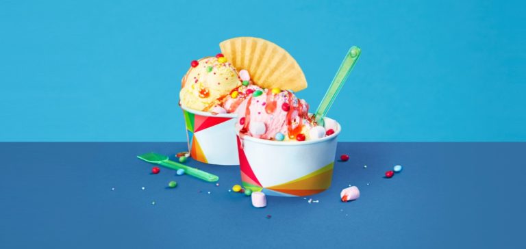 two tubs of ice cream with colour chocolate sprinkles and strawberry sauce