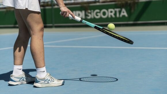 Female tennis player lifting up the ball with the racket