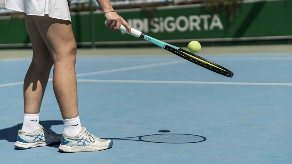 Female tennis player lifting up the ball with the racket