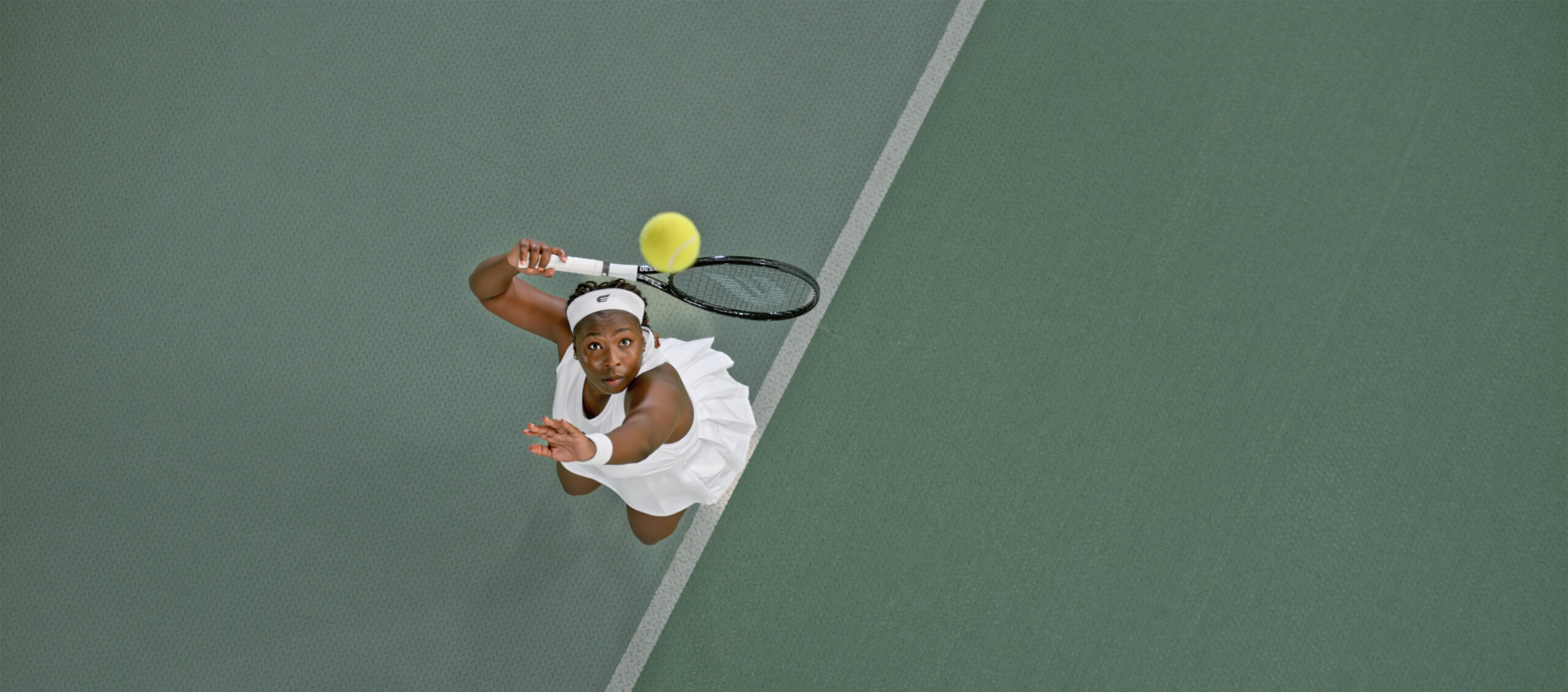 Woman photographed mid-serve while playing tennis