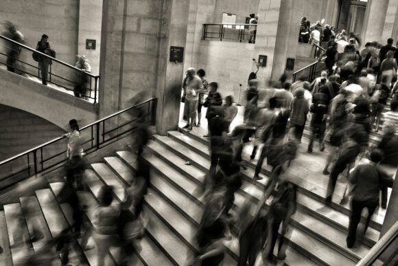 people rushing up and down stairs in a marble building.