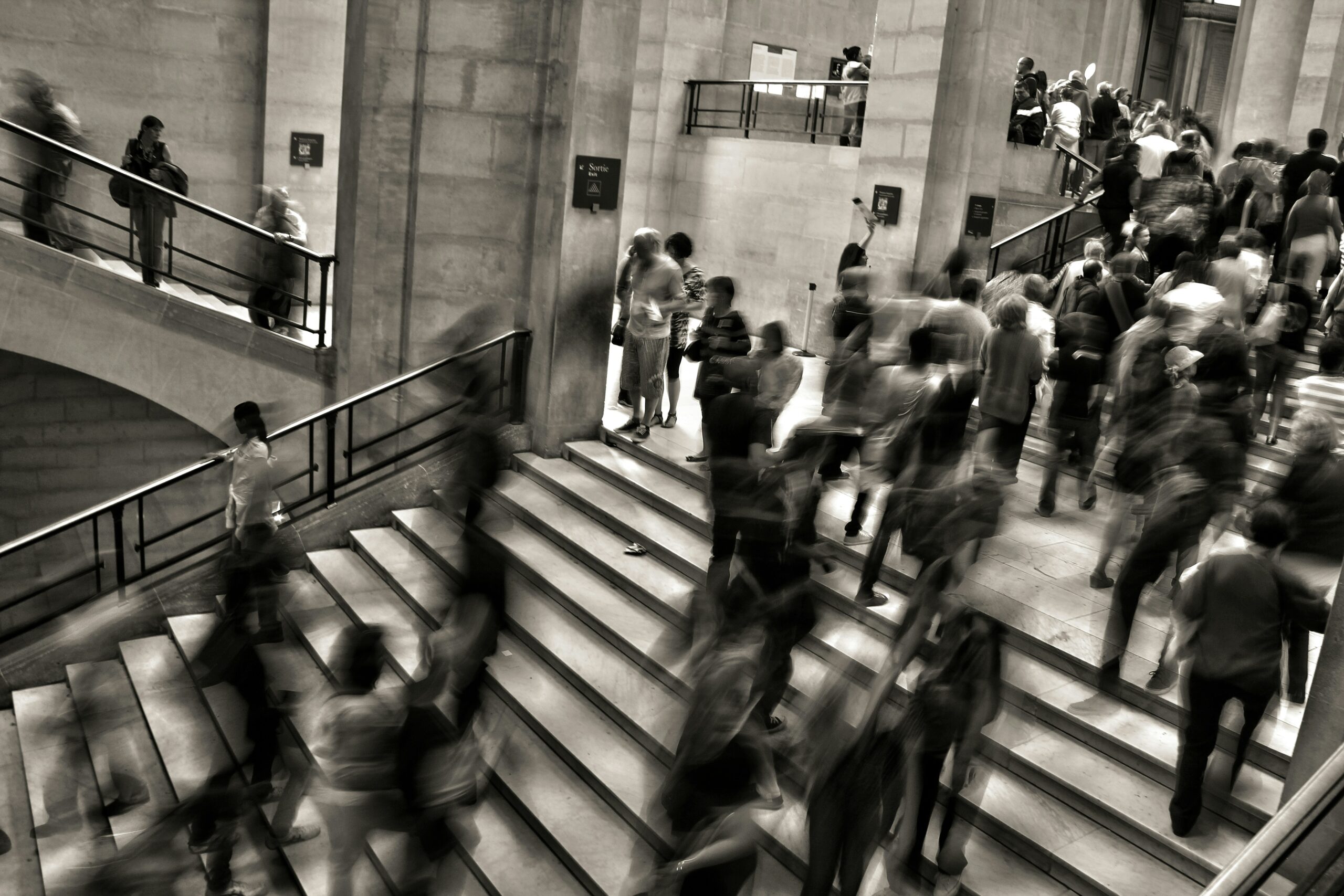 people rushing up and down stairs in a marble building.