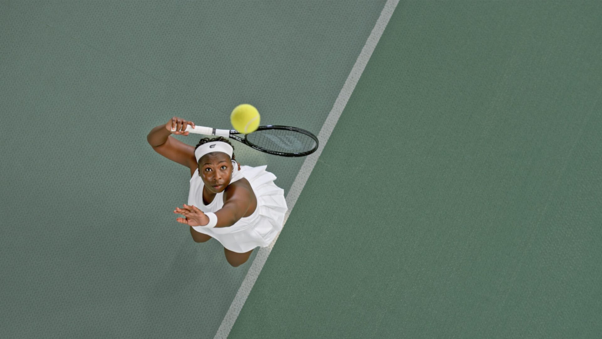 Woman photographed mid-serve while playing tennis
